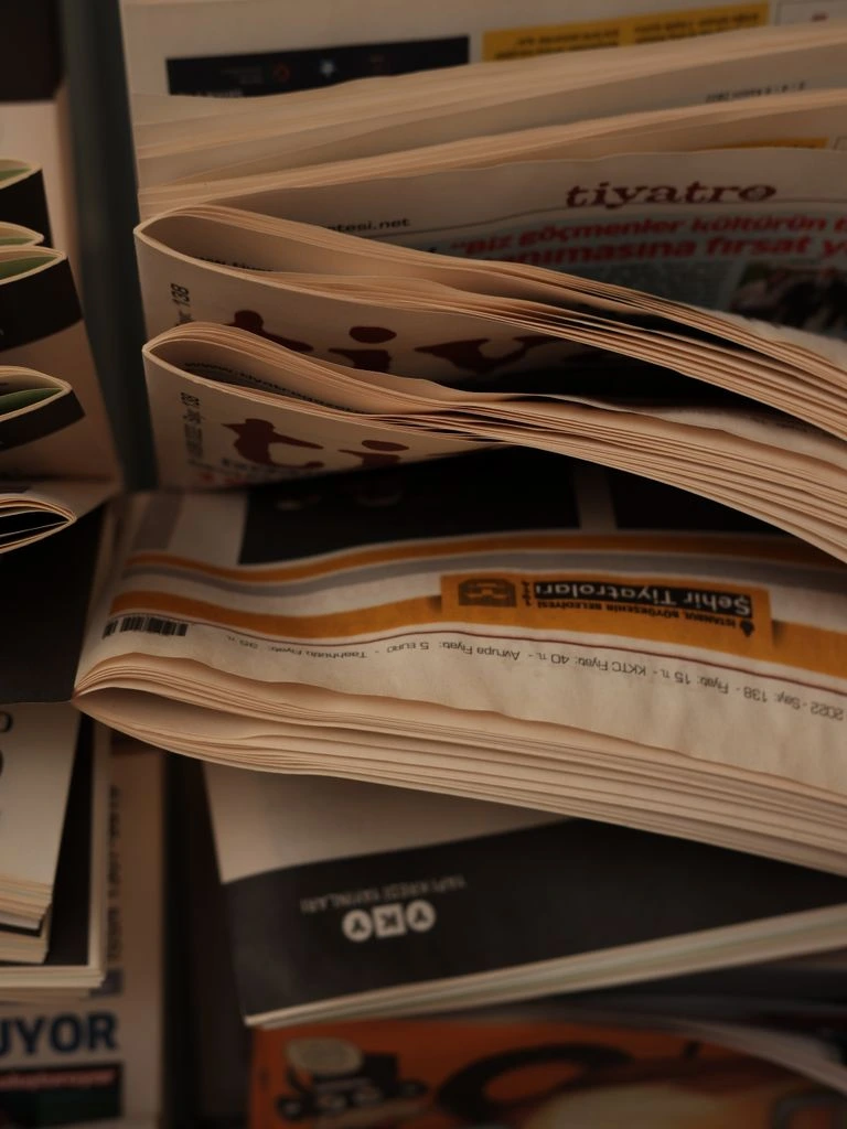 A folded morning paper beside a cup of coffee on a wooden desk